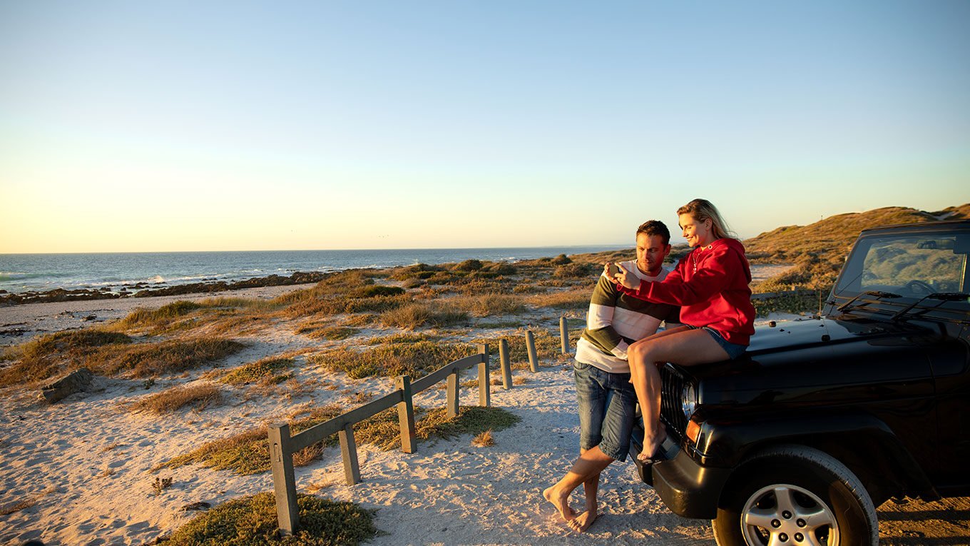 pareja en un auto rentado en la playa